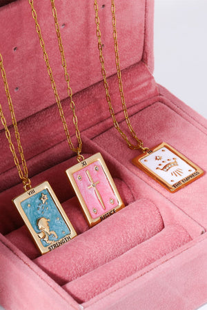 Tarot card pendant necklaces in light blue, pink, and white with gold chains.