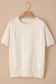 Ivory knit top with short sleeves and daisy appliqué details.