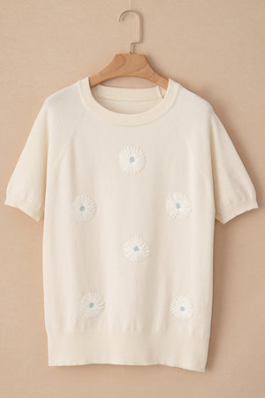 Ivory knit top with short sleeves and daisy appliqué details.