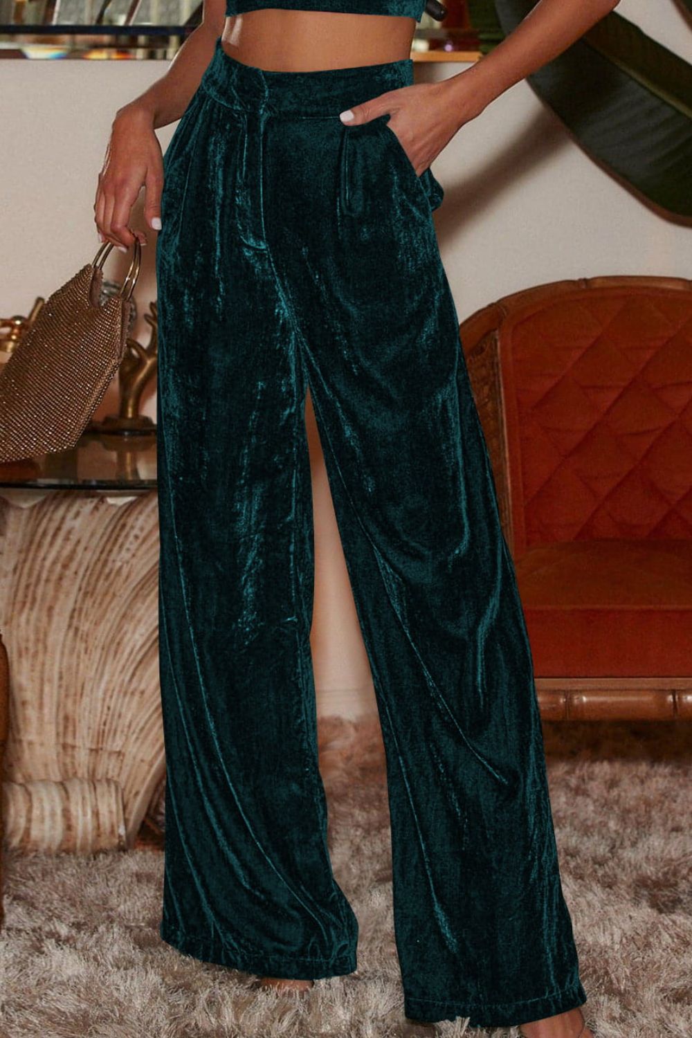 Dark green velvet palazzo trousers with high waist and side slit, shown with a pocket detail.