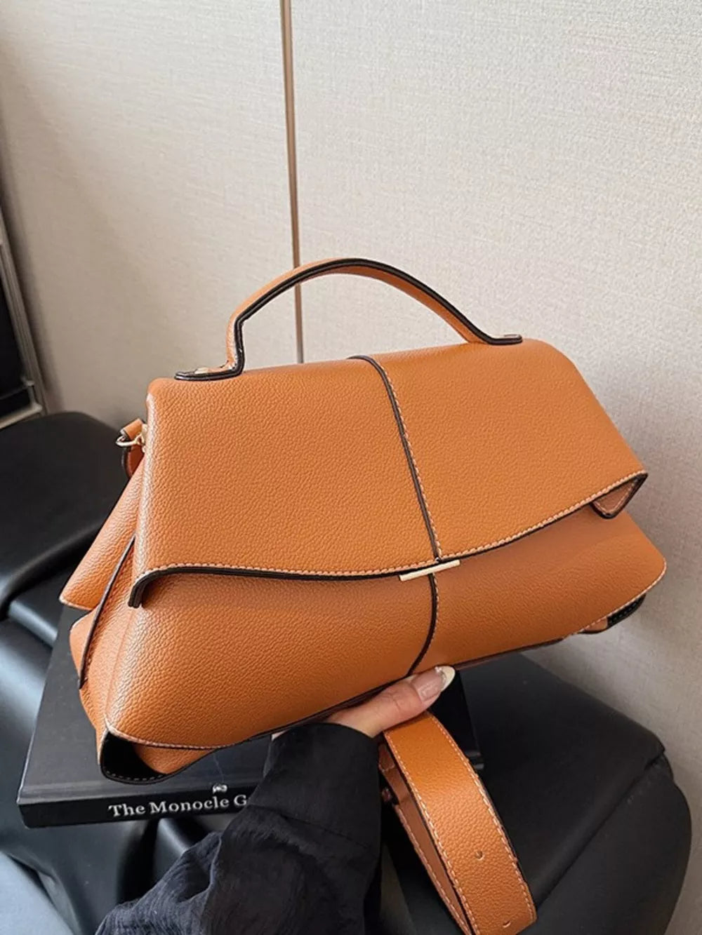 Brown textured geometric flap shoulder bag with top handle and adjustable strap.