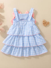 Blue gingham baby dress with tiered ruffles and pink bow accents on back.