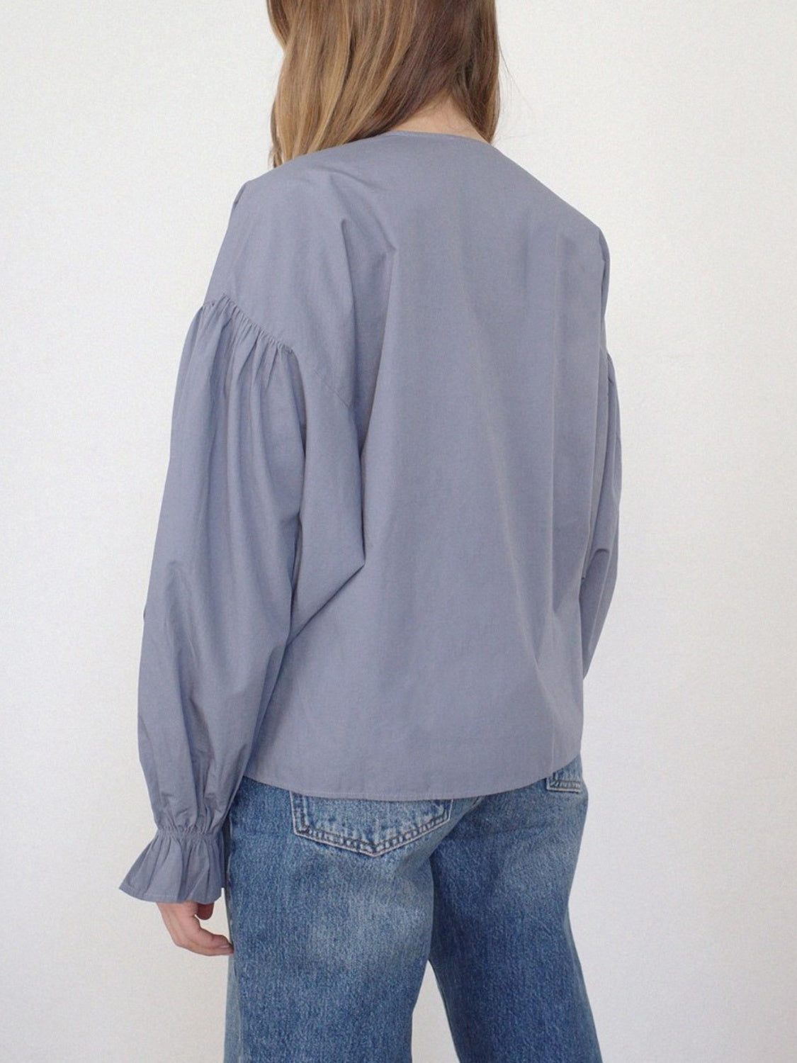 Lavender blouse with gathered sleeves and ruffled cuffs, paired with jeans.