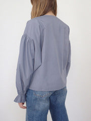 Lavender blouse with gathered sleeves and ruffled cuffs, paired with jeans.
