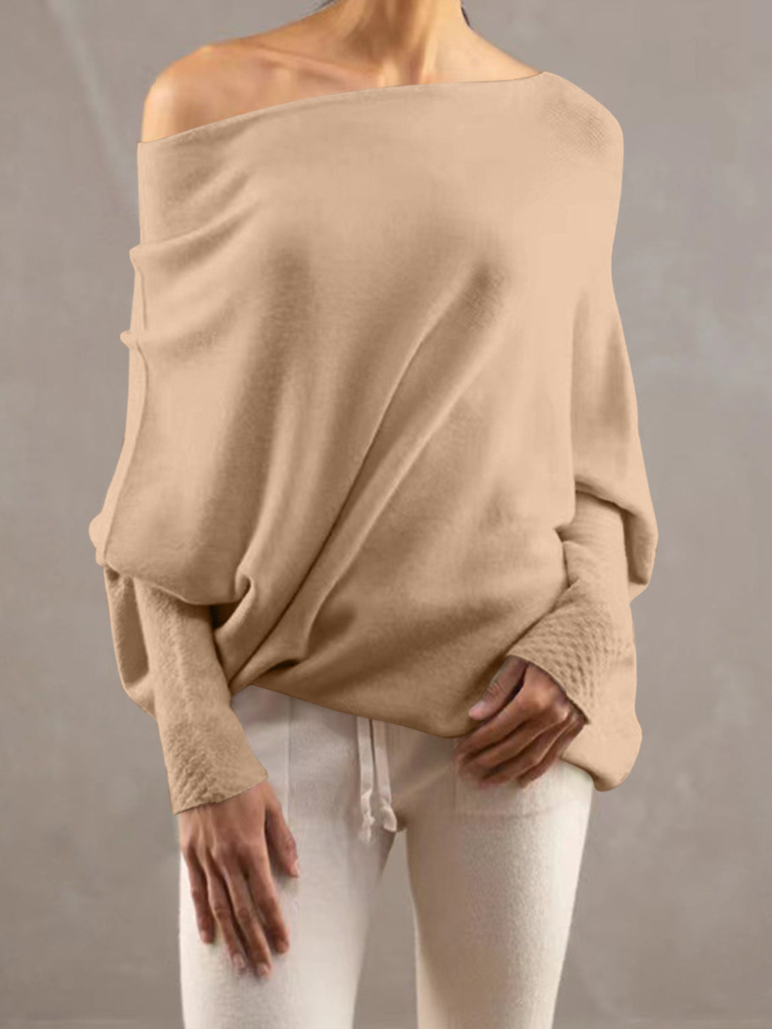 Cream off-shoulder knit sweater with textured cuffs and batwing sleeves.