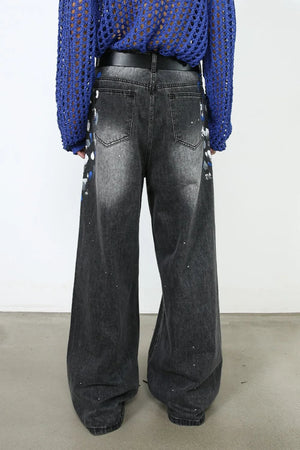 Dark wash denim jeans with painterly blue and white accents, wide flare leg, and distressed details.