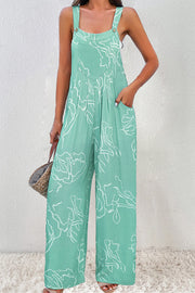 Turquoise wide-leg jumpsuit with white botanical print, button straps, and pockets.
