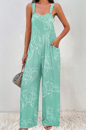 Turquoise wide-leg jumpsuit with white botanical print, button straps, and pockets.