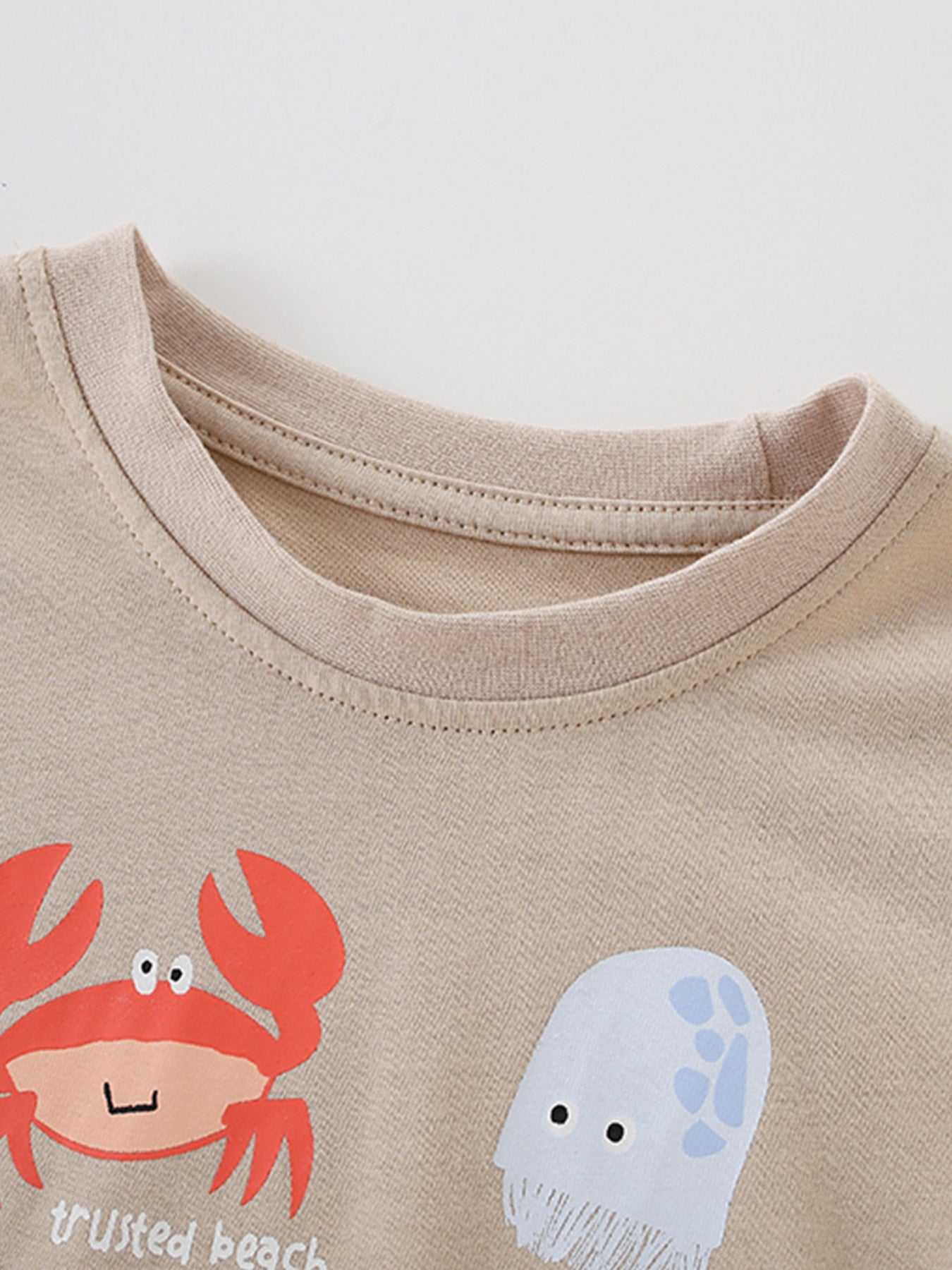Beige cotton toddler t-shirt with colorful crab and jellyfish graphic.