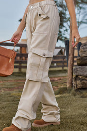 Tan utility cargo pants with wide legs and buttoned flap pockets.