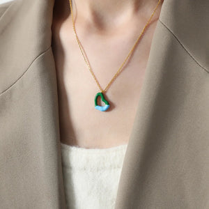 Gold necklace with a two-tone green and blue heart pendant.
