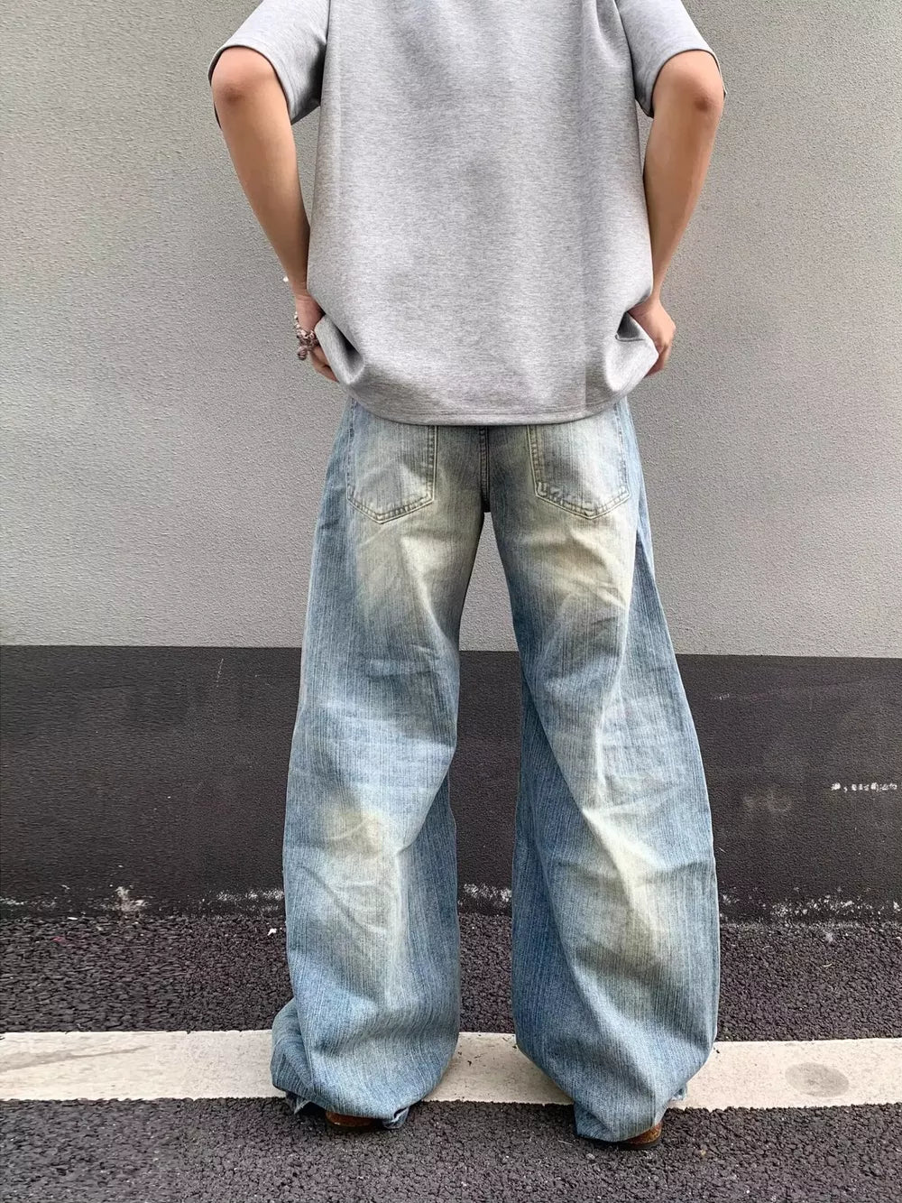 Distressed light wash denim wide-leg jeans with pocket detail.