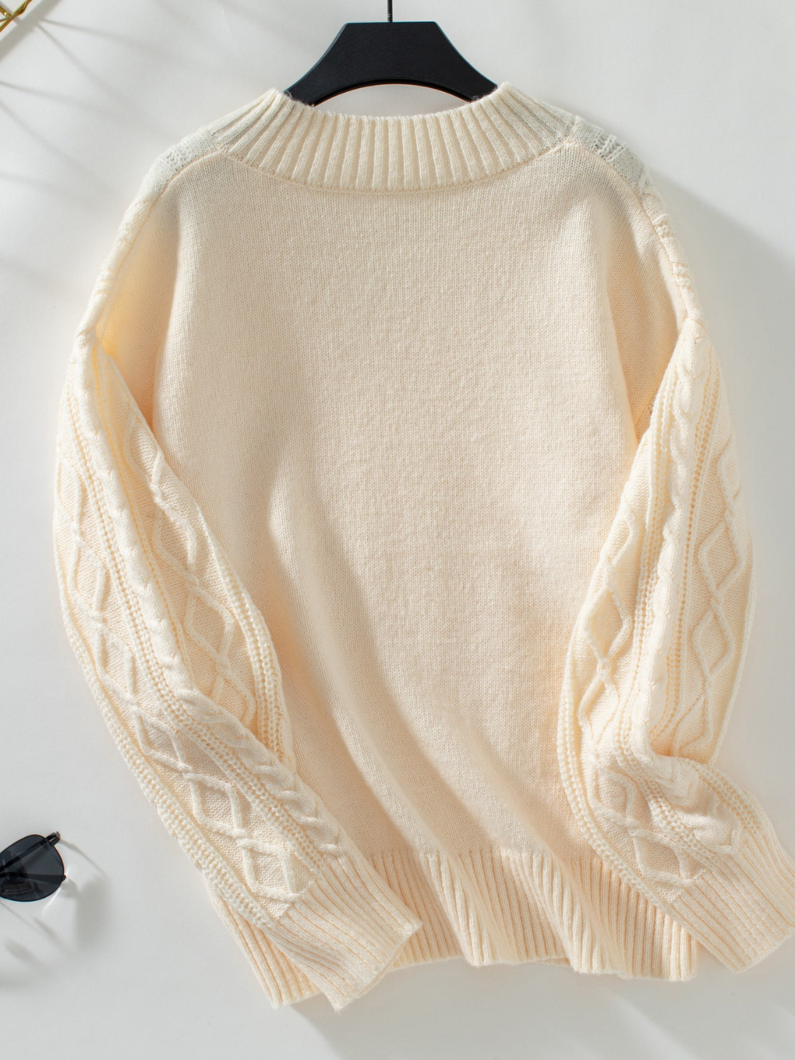 Cream cable knit sweater with diamond pattern sleeves and keyhole neck detail.