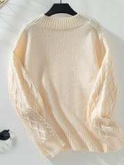 Cream cable knit sweater with diamond pattern sleeves and keyhole neck detail.
