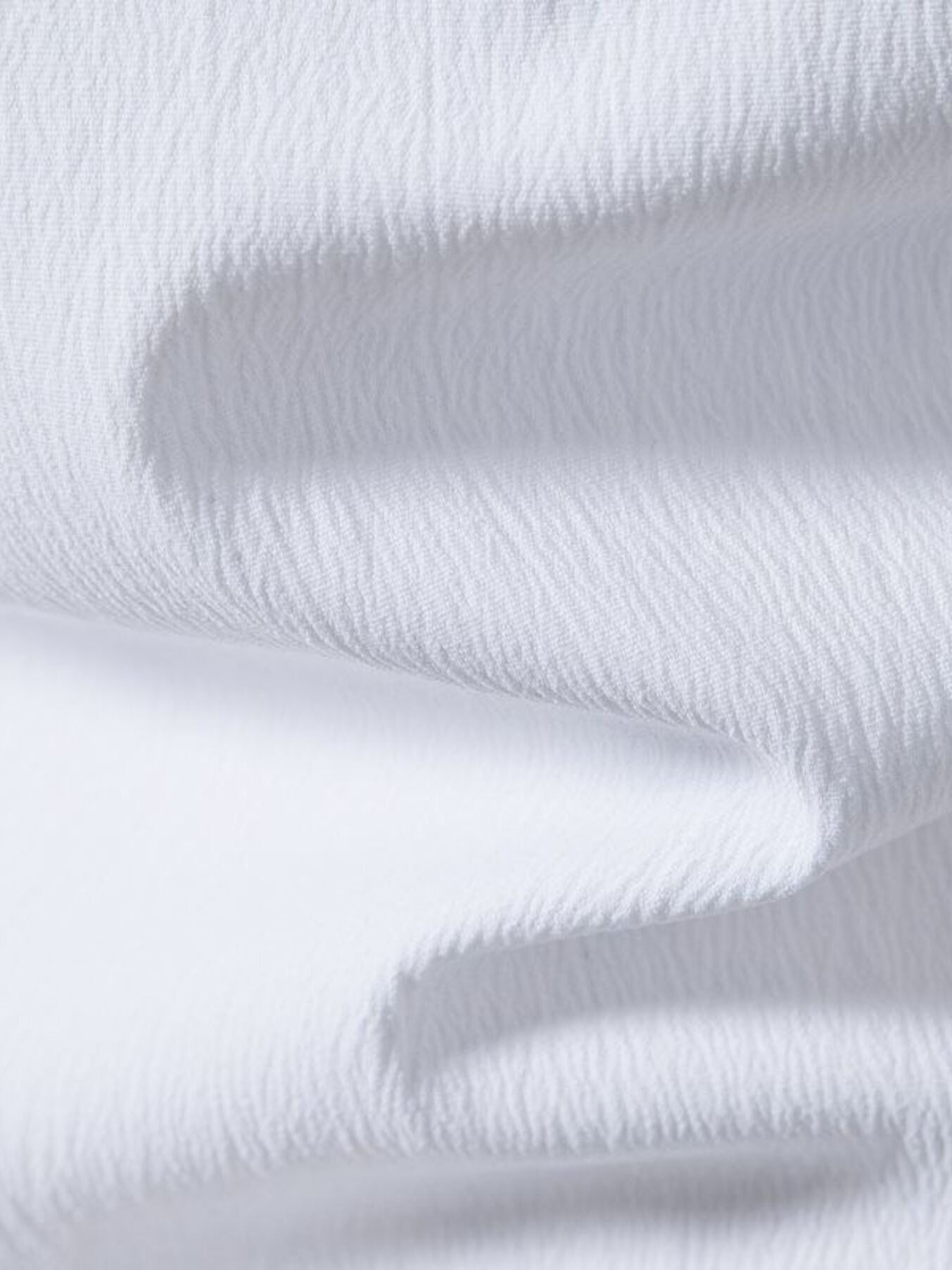 White cotton short sleeve shirt with textured fabric and band collar detail.