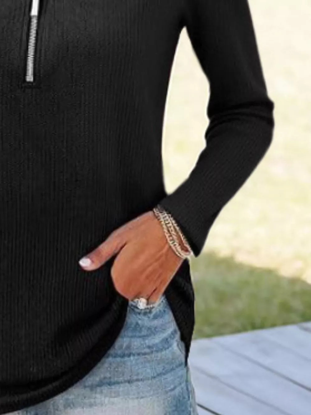 Black ribbed knit half-zip sweater with long sleeves and a silver zipper detail.