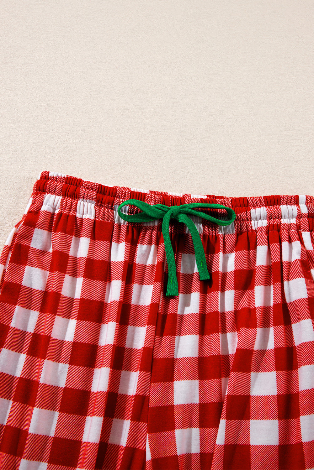 Festive red and white gingham pajama shorts with green drawstring detail.