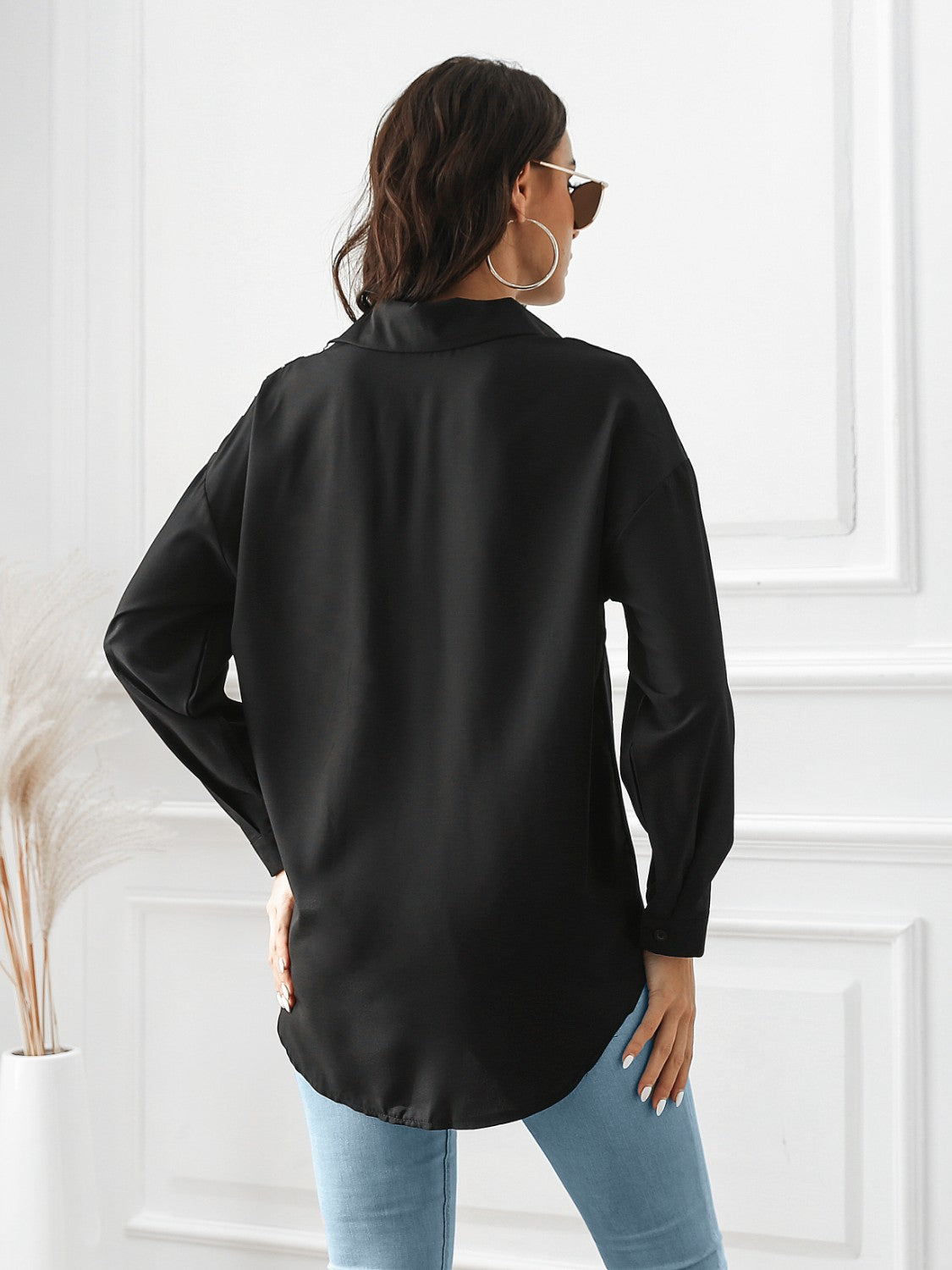 Black button-down shirt with long sleeves and a curved hem.