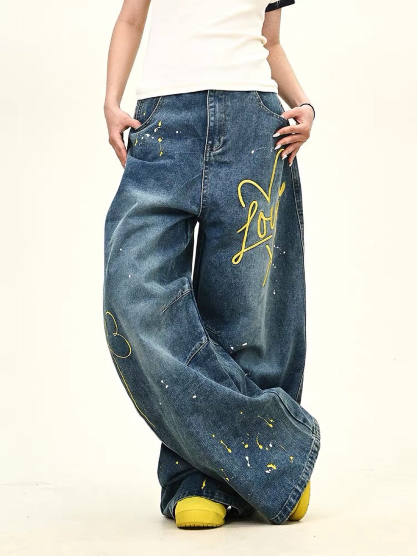 Oversized blue wide-leg jeans with yellow love graphic and paint splatters