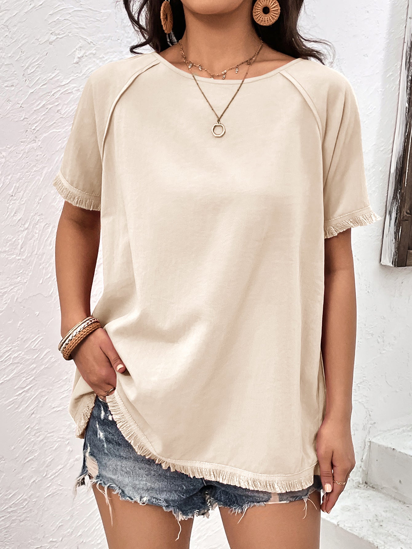 Cream raglan sleeve tee with fringed hem and cuffs, styled with denim shorts.