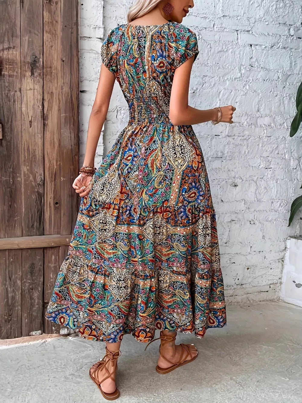 Vibrant tiered maxi dress with smocked bodice and colorful paisley print.
