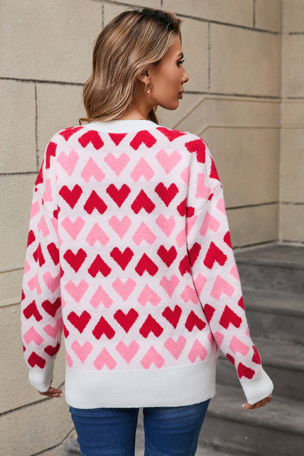 White knit sweater with allover red and pink heart pattern, crew neck, long sleeves.