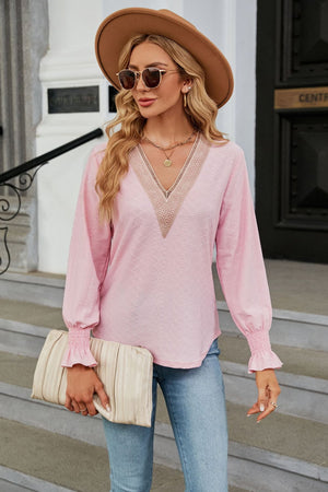 Blush pink textured V-neck blouse with lace trim and smocked cuffs.
