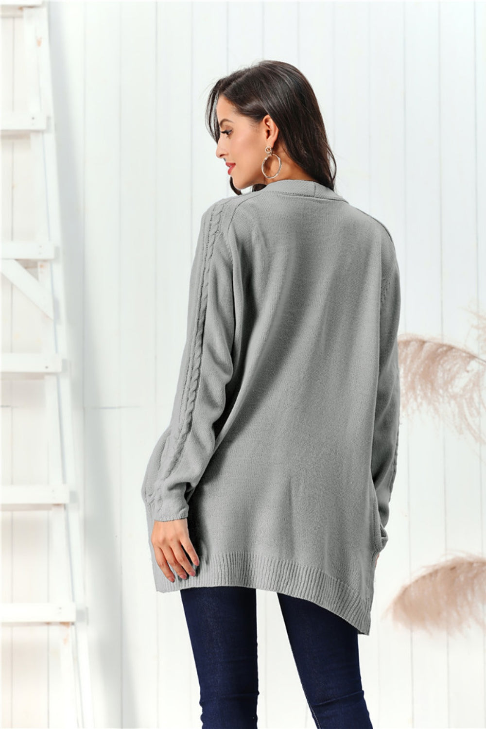 Gray cable knit open front cardigan with braided sleeve detail.