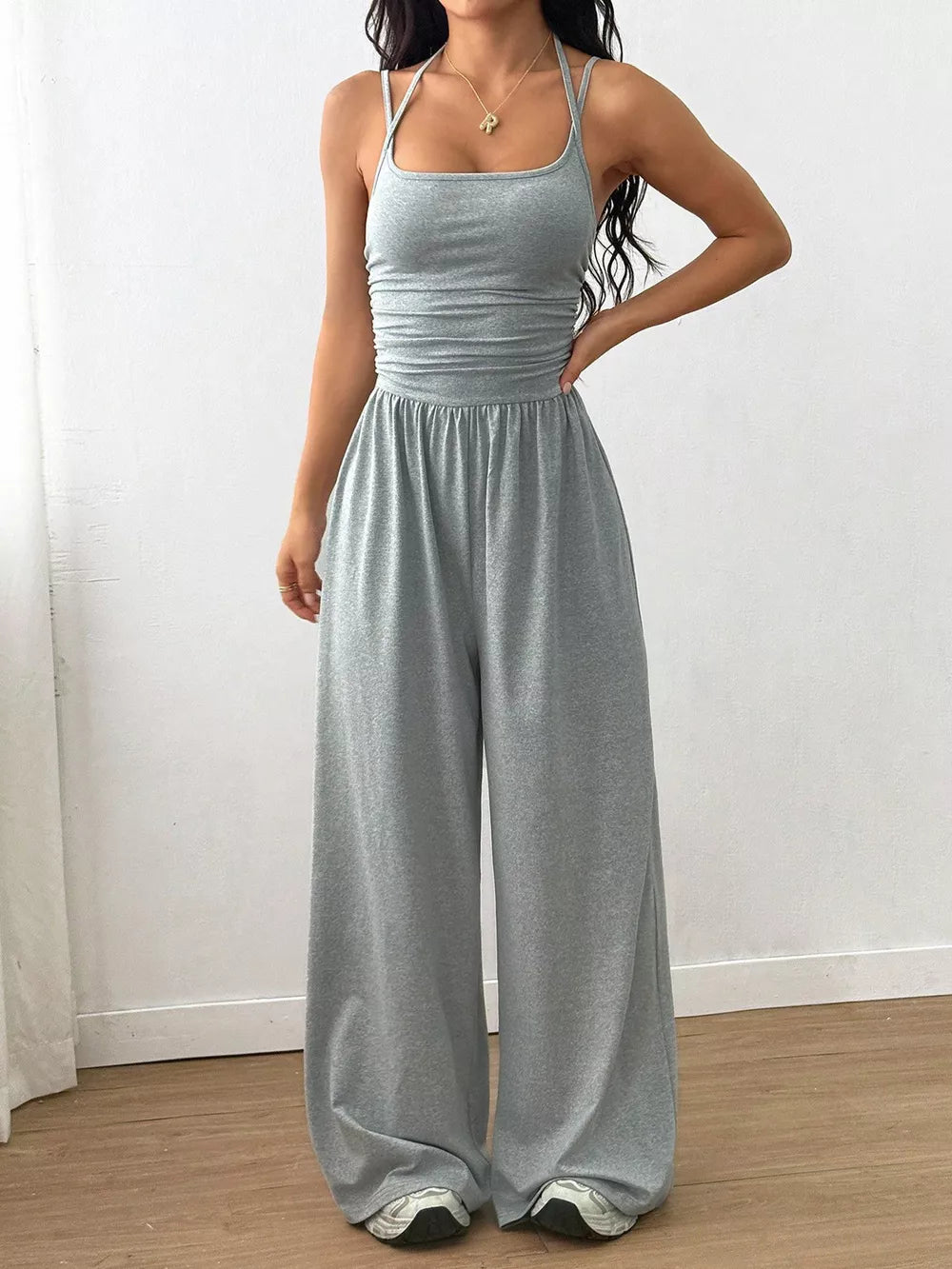 Gray wide-leg jumpsuit with spaghetti straps and ruched waist detail.