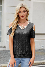 Black sequin cold shoulder blouse with white trim and criss-cross neckline.