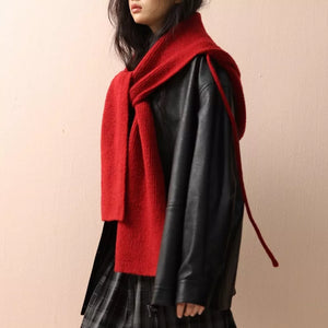 Red knit hooded scarf with tie detail, worn over a black jacket.