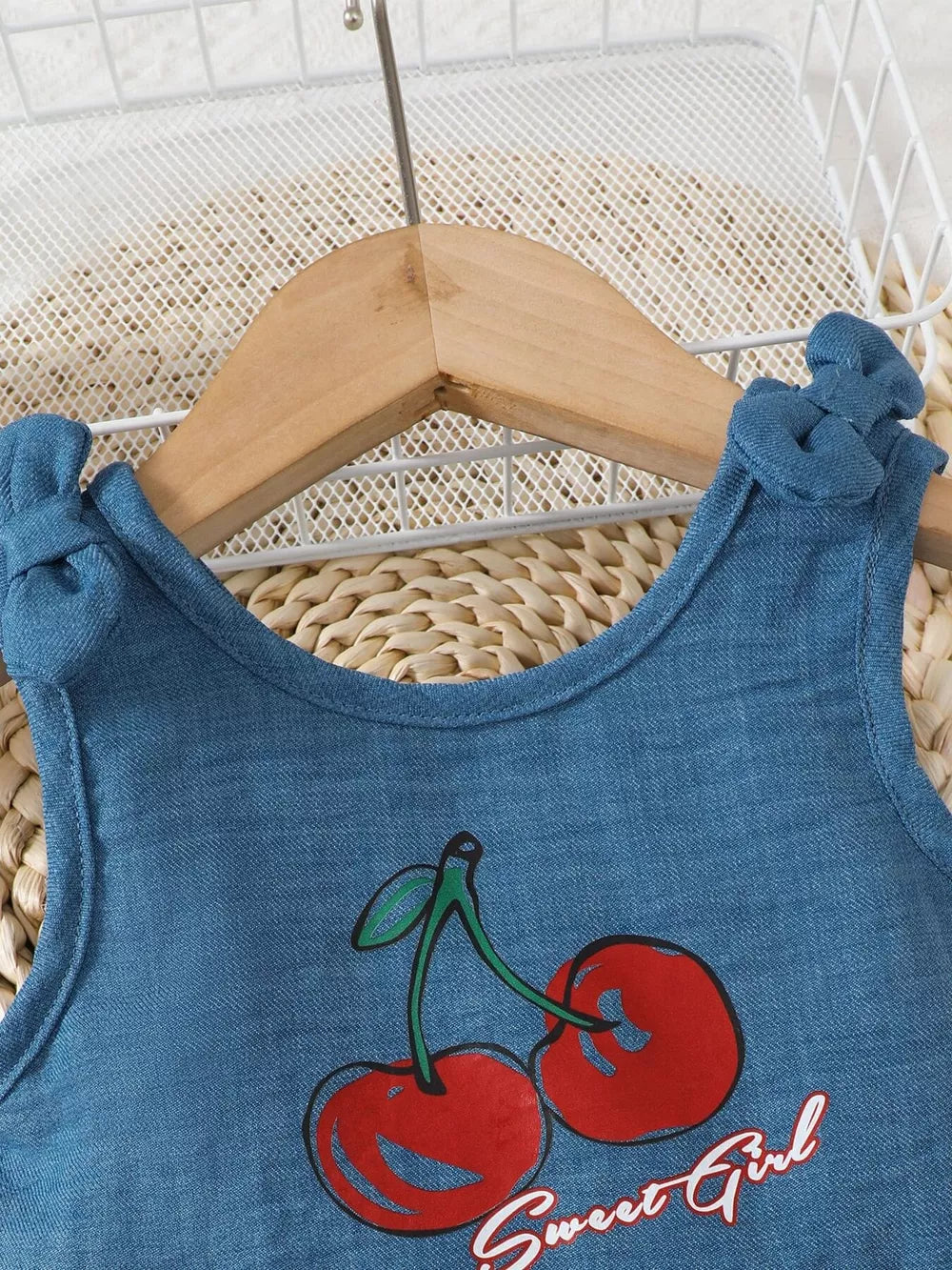 Blue peplum tank with cherry graphic and bow shoulder straps.