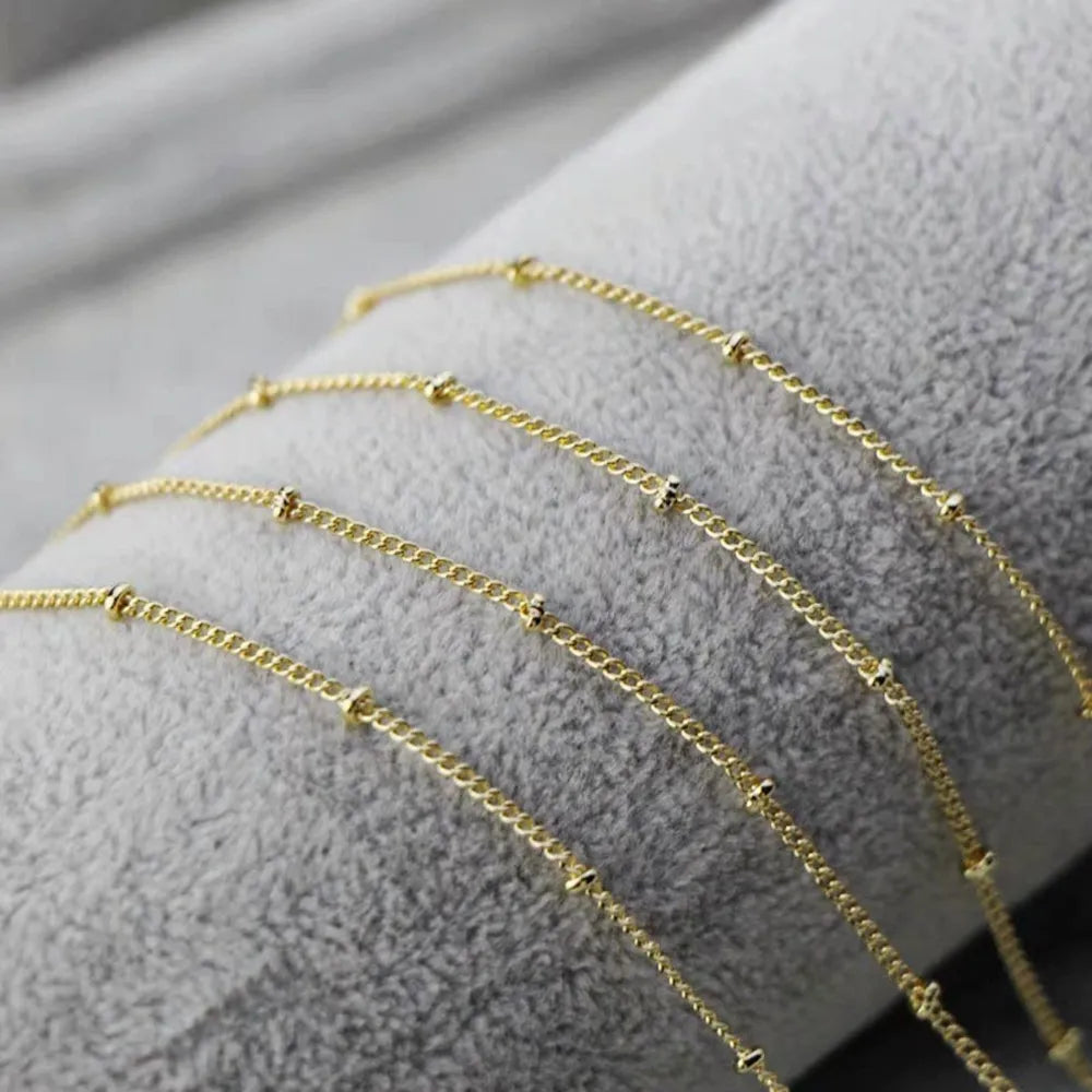 Gold beaded chain necklace with small gold beads spaced along the chain.