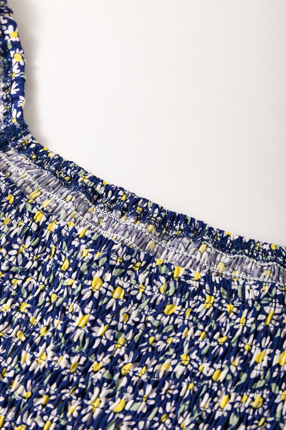 Dusty blue smocked peplum blouse with a daisy print and square neckline detail.
