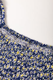 Dusty blue smocked peplum blouse with a daisy print and square neckline detail.