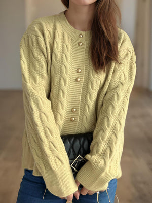 Pastel yellow cable knit cardigan with puff sleeves and gold buttons.