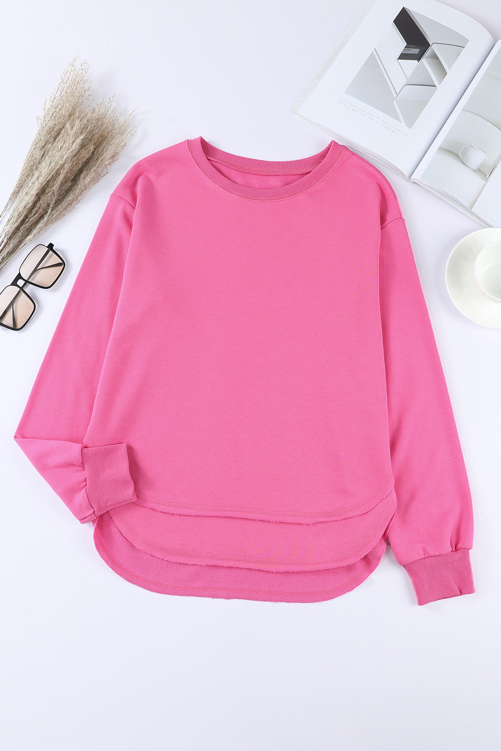 Rose pink sweatshirt with crew neck, long sleeves, and asymmetric hemline.