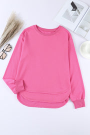 Rose pink sweatshirt with crew neck, long sleeves, and asymmetric hemline.