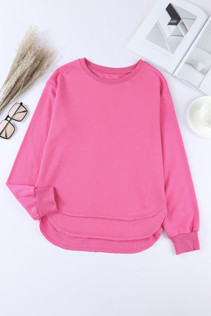 Rose pink sweatshirt with crew neck, long sleeves, and asymmetric hemline.