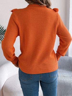 Orange textured knit sweater with ruffle yoke detail and crew neck.