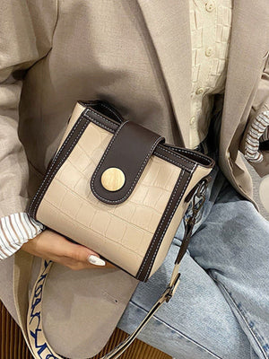 Khaki crocodile pattern mini crossbody bag with dark brown trim and gold button closure.