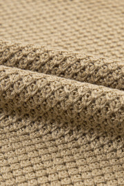Khaki textured knit turtleneck sweater with cap sleeves and a waffle knit pattern.