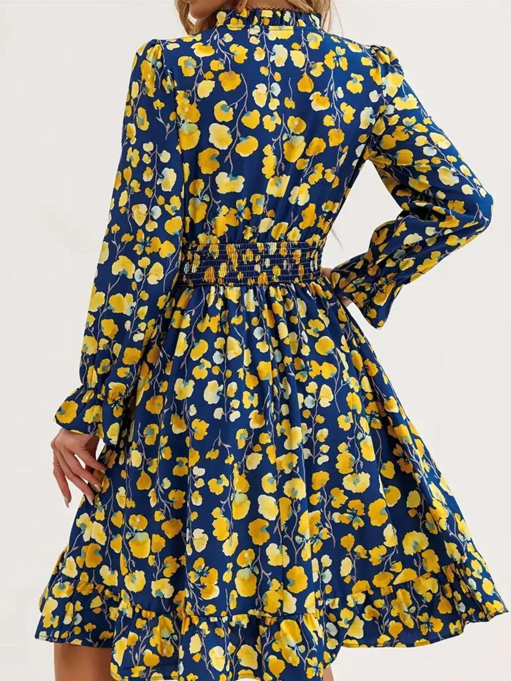Romantic floral smocked dress in navy with yellow flowers, long sleeves, and ruffled hem.