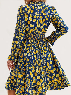 Romantic floral smocked dress in navy with yellow flowers, long sleeves, and ruffled hem.