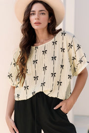 Beige gauze blouse with black bow print and gathered sleeves.