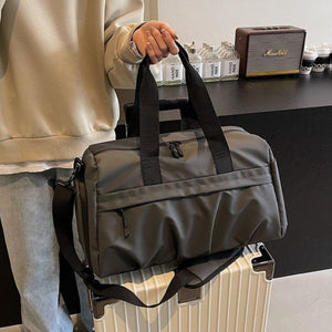 Gray nylon travel duffel bag with multiple zippered pockets and adjustable shoulder strap.