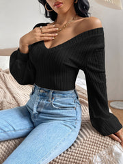 Black textured chevron blouson top with V-neck and long sleeves styled with jeans.