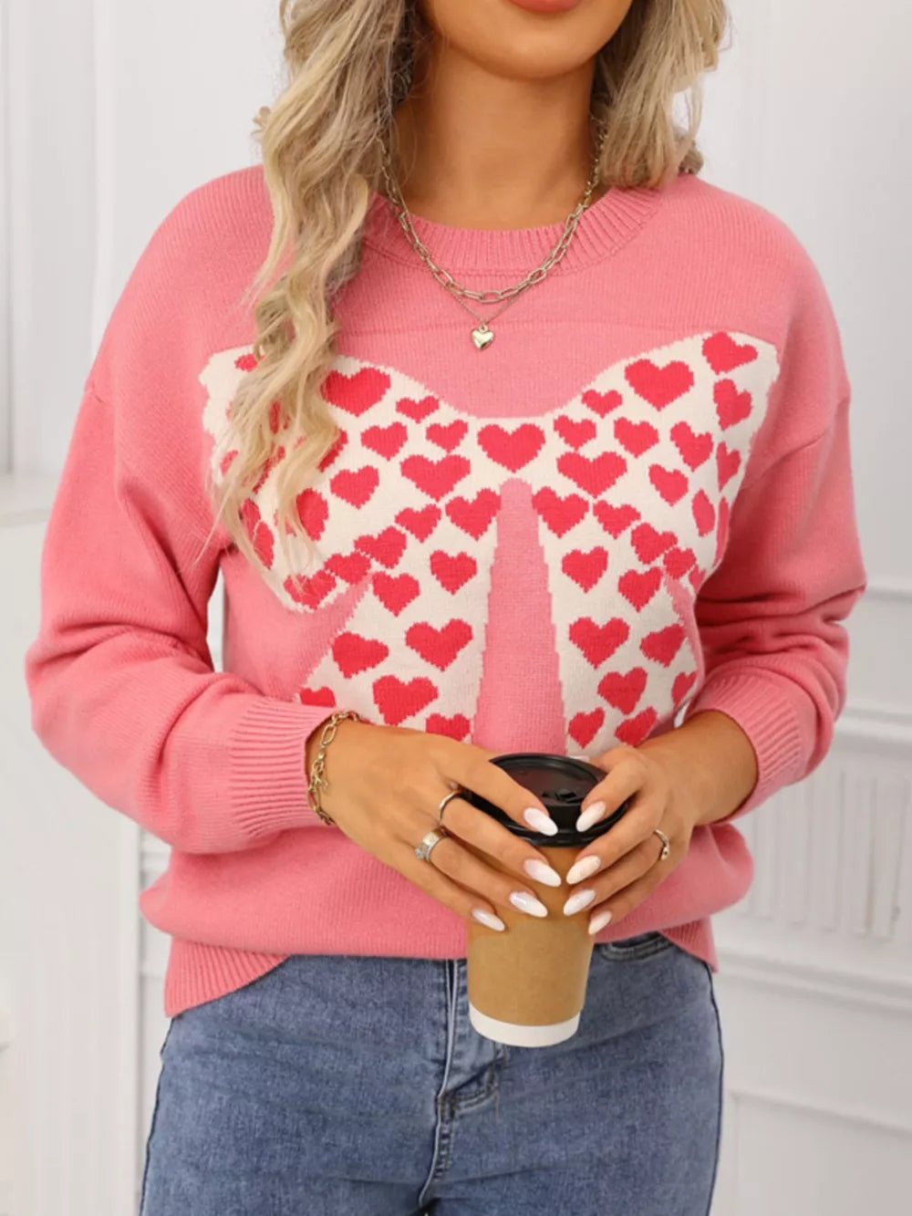 Pink acrylic knit sweater with heart bow pattern and round neck.