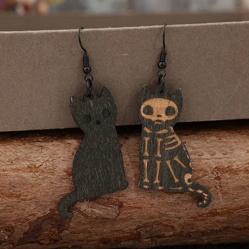 Black laser-cut cat earrings, one with skeleton detail, made of wood.