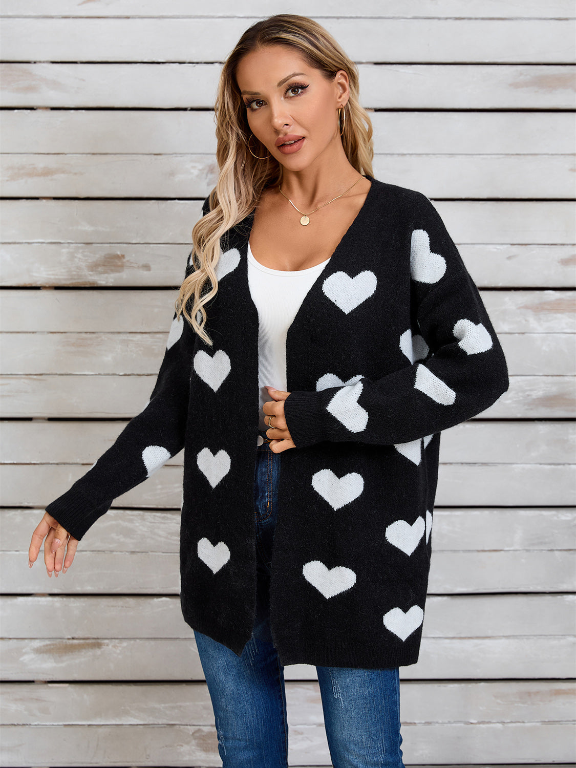 Black acrylic cardigan with white intarsia hearts, V-neck, long sleeves.